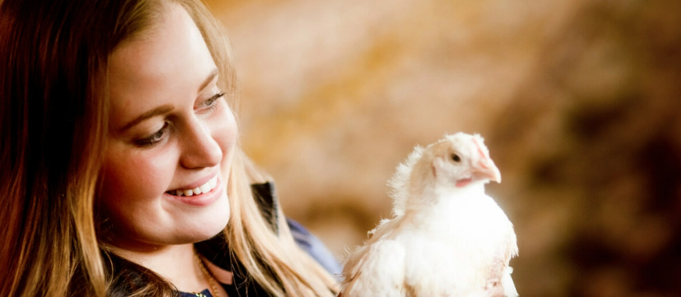 Smiling woman holding a chicken